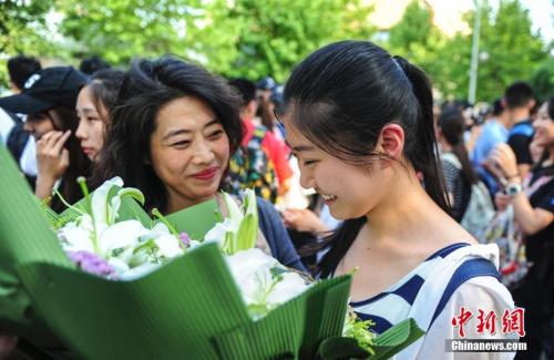 資料圖：山東濟南眾多考生手捧鮮花在家長的簇?fù)硐職g快告別高考。中新社記者 張勇 攝