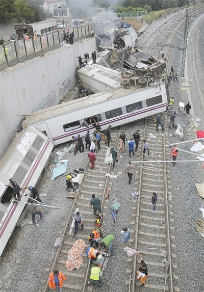 24日，救援人員在西班牙列車脫軌現(xiàn)場。一節(jié)車廂被強(qiáng)大的慣性拋上鐵道邊的高臺。