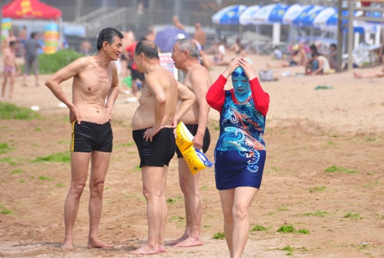 2013年7月3日，山東青島青島高溫來襲，“青島大媽”不懼滸苔，戴著“強(qiáng)盜面具”出現(xiàn)在海水浴場(chǎng)消暑降