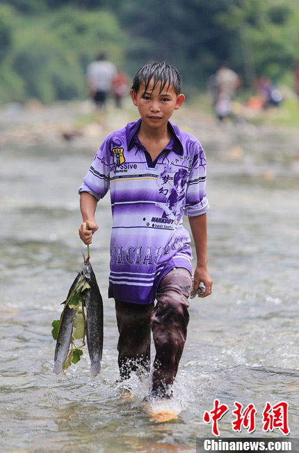 圖為7月9日，一名男孩在鬧魚節(jié)活動中抓到了兩條魚。譚凱興 攝