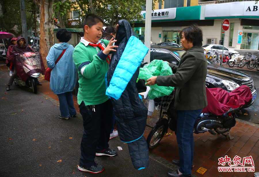 學(xué)校門口，家長給孩子帶來了御寒的厚衣服。