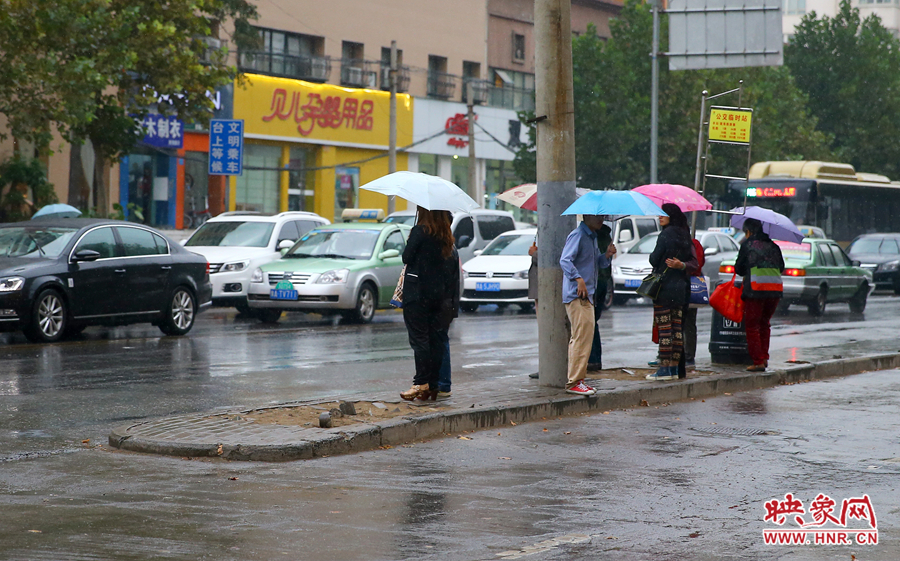 秋雨中等待公交的市民