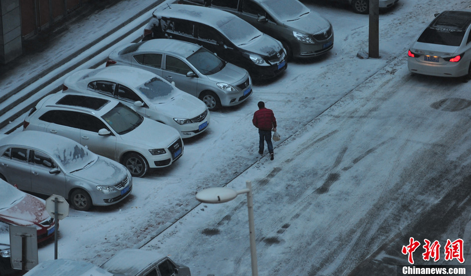 11月18日，行人在沈陽街頭的積雪中穿行。