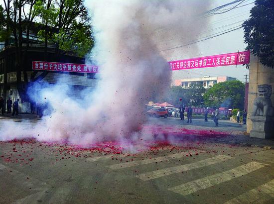 市民在普洱市主干道振興大道的金孔雀交通運(yùn)輸集團(tuán)有限公司門(mén)前燃放鞭炮，公司門(mén)前掛著“貪腐份子沈培平被查處，罪有應(yīng)得，大快人心?！钡臈l幅