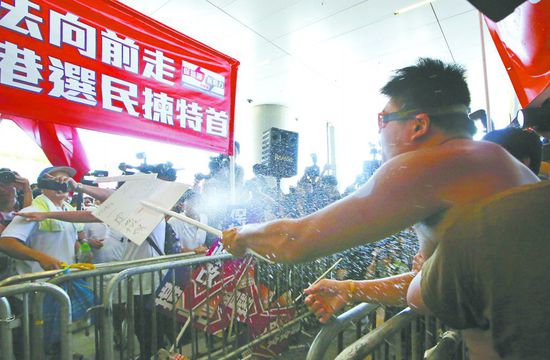 17日，在香港立法會(huì)外，一名反對(duì)政改的男子向支持派人群投擲標(biāo)牌。