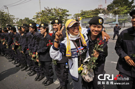 2013年12月03日,曼谷總理府與曼谷警署允許反政府示威民眾進入,雙方進入暫時“停戰(zhàn)”狀態(tài)迎接泰王生日。曼谷警察總署,女警們手持鮮花送給反政府示威民眾。圖片來源:Manish Swarup/東方IC