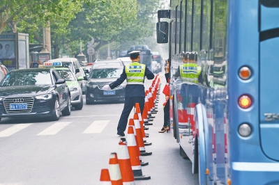 省人民醫(yī)院南門的路中間擺放反光錐，交警示意由西向東車輛從前方繞行。