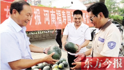 河南福壽園區(qū)域總經理吳正宗（左一）、東方今報發(fā)行中心副總監(jiān)王路喜（中）在街頭給市民送瓜