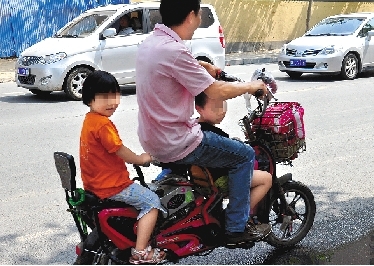 周先生騎著一輛低矮的電動(dòng)車帶著一對(duì)兒女，很不安全。