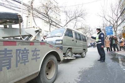 聯(lián)合執(zhí)法人員將市民舉報的違法占道經(jīng)營車輛拖走暫扣