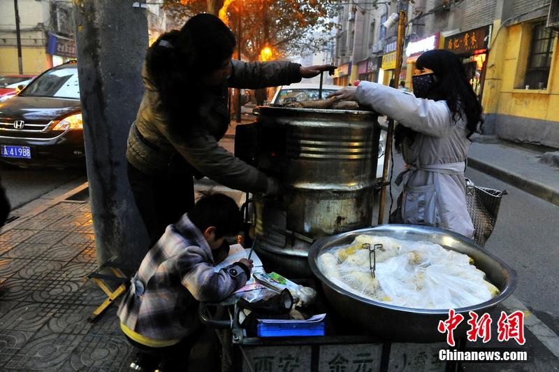 男孩西安路燈下寫作業(yè) 媽媽邊賣紅薯邊輔導