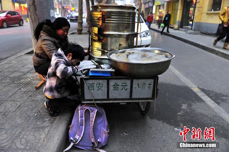 男孩西安路燈下寫作業(yè) 媽媽邊賣紅薯邊輔導