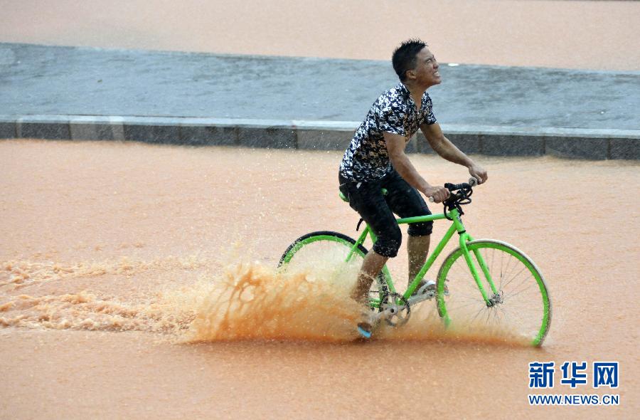 5月11日，一名行人在深圳街頭冒雨騎行。