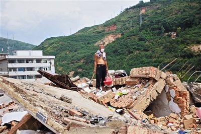 8月9日,龍頭山鎮(zhèn),一位老者在自家房屋廢墟上尋找家當。