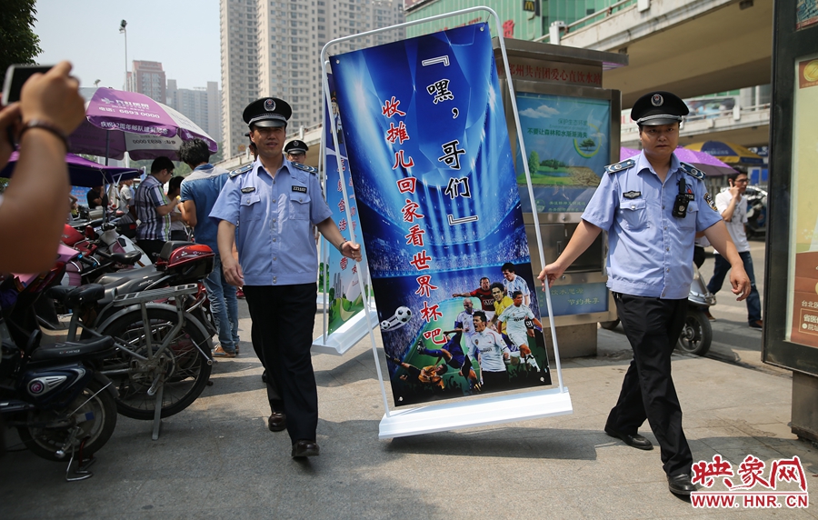 7月2日上午，鄭州市紫荊山地鐵站出入口，執(zhí)法人員抬著寫有勸導(dǎo)語的宣傳板，前往占道經(jīng)營攤位“圍觀執(zhí)法”