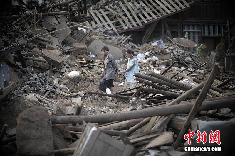 2014年8月5日，云南昭通龍頭山鎮(zhèn)老街，一對(duì)夫妻從居住房屋的廢墟中走過。