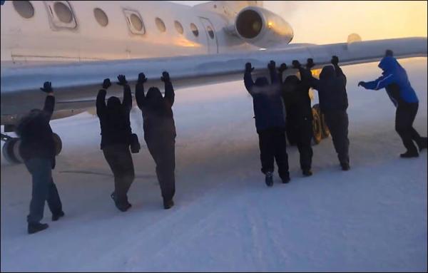 　伊加爾市一架客機起飛前被凍在了跑道上。飛機上的乘客不得不下來推飛機。