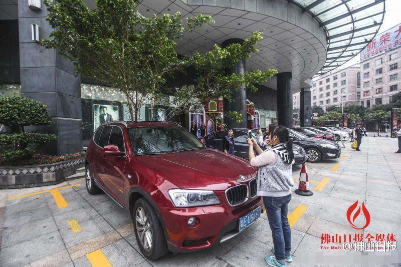 一輛停在停車位上的寶馬轎車，被墜落的樹枝砸中，樹枝徑直插入車內(nèi)，現(xiàn)場(chǎng)引發(fā)不少市民圍觀拍照。