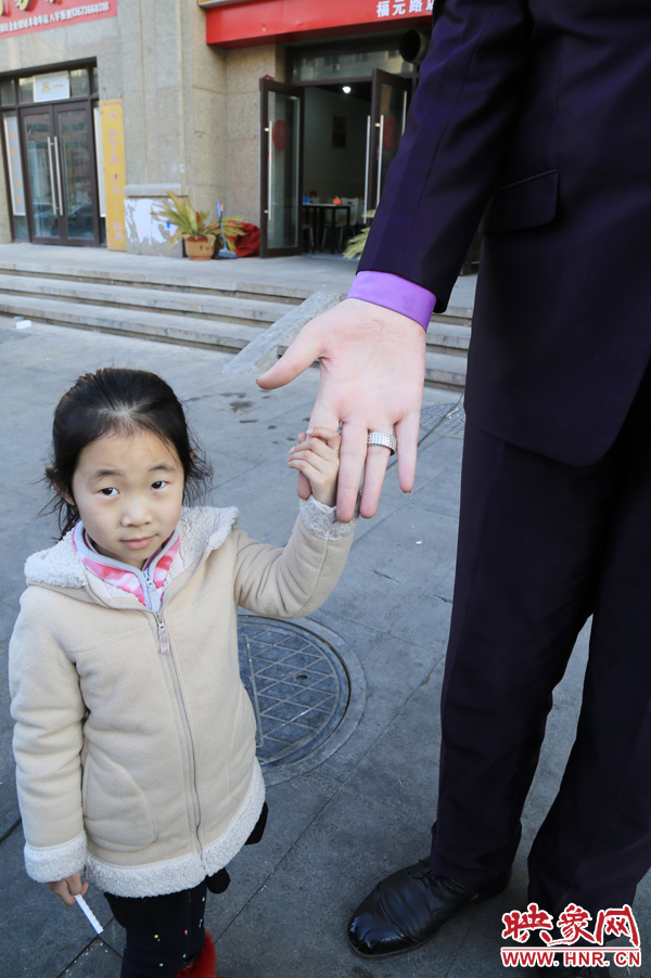 巨人“張歡”牽著一名漂亮的小女孩，兩人的手大小對比非常明顯。