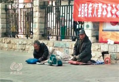 工人體育場北路，兩位乞討者路邊乞討，并輪流扮成“病人”（躺地者）。 央視截圖