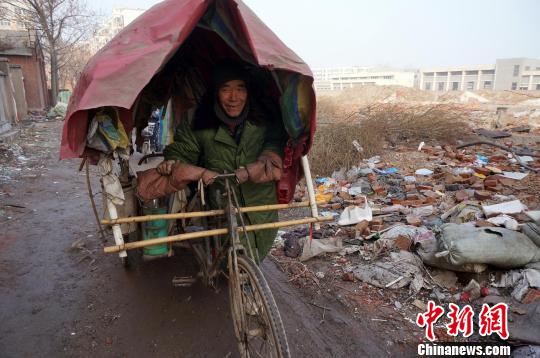 圖為老人走出窩棚，推著三輪車準(zhǔn)備出去撿拾廢品。周小云 攝